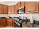 Kitchen featuring stainless appliances, black countertops, and wood cabinets at 5721 W Molly Ln, Phoenix, AZ 85083