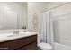 This bathroom has a sleek vanity and a shower/tub with a white shower curtain at 5875 N 195Th Dr, Litchfield Park, AZ 85340