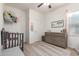This bright bedroom features a ceiling fan, a neutral color palette, and a gray dresser and crib at 5875 N 195Th Dr, Litchfield Park, AZ 85340