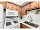 Features a white gas range, wooden cabinets, stainless double sink, and white countertop at 849 E Lancaster Cir, Florence, AZ 85132