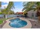 Private backyard featuring a kidney-shaped pool, palm trees, lush landscaping and a covered outdoor dining area at 974 E Palomino Way, San Tan Valley, AZ 85143