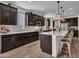 Spacious kitchen with dark cabinets, granite countertops, a large island with seating, and stainless steel appliances at 9821 E Supernova Dr, Mesa, AZ 85212