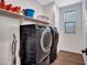 Modern laundry room with high-end washer and dryer, floating shelves, and wood-look flooring at 9821 E Supernova Dr, Mesa, AZ 85212