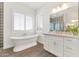 Bright bathroom with a modern soaking tub, shutters, vanity with white cabinets and stone countertop at 10147 W Camino De Oro --, Peoria, AZ 85383