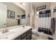 Bathroom with dual sinks, dark cabinets, and shower with black and white curtain at 10249 W Redbird Rd, Peoria, AZ 85383