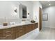 Bright bathroom featuring wood cabinets, a rectangular mirror, and unique gold sconce lighting at 109 E Hayward Ave, Phoenix, AZ 85020