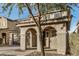 Warm home exterior featuring a covered porch with an arched entryway and two-car garage at 11918 W Yearling Ct, Peoria, AZ 85383