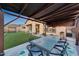 Outdoor dining area with a table, chairs, and artificial grass against a house with a patio at 12008 S 186Th Dr, Goodyear, AZ 85338