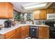 Well-lit kitchen featuring wooden cabinets, a black dishwasher, and a corner window with plants at 18435 N 36Th Ave, Glendale, AZ 85308