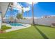 Landscaped backyard featuring artificial turf, pool, and palm trees, perfect for outdoor activities and relaxation at 1847 W Isleta Ave, Mesa, AZ 85202