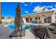 A pool with an umbrella and lounge chairs sits in a backyard with a covered patio and outdoor furniture at 1847 W Isleta Ave, Mesa, AZ 85202