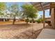 Serene backyard featuring decorative rock, a patio cover, and mature landscaping at 213 S 225Th Ln, Buckeye, AZ 85326