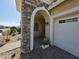 Close-up view of home exterior featuring an archway entrance with stone accents and a 2-car garage at 24986 N 172Nd Ln, Surprise, AZ 85387