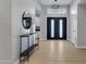 Bright foyer featuring modern double doors, light wood floors, stylish console table, and a round mirror at 3060 W Ironwood Cir, Chandler, AZ 85226