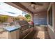 Covered outdoor kitchen boasts a stainless steel grill, prep area, blue-tiled accents, and a ceiling fan for comfortable cooking at 3121 N Loma Vista Dr, Mesa, AZ 85213