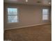 A large bedroom with neutral walls and carpet featuring two windows that provide natural light at 40232 W Marion May Ln, Maricopa, AZ 85138