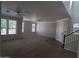 A spacious living room with carpet, multiple windows, ceiling fans, and access to the staircase at 40232 W Marion May Ln, Maricopa, AZ 85138
