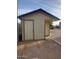 Exterior view of a small outbuilding with door and overhanging roof at 40232 W Marion May Ln, Maricopa, AZ 85138