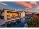 Sparkling pool reflecting the sunset, with a covered patio, outdoor seating and desert landscaping at 41006 N Noble Hawk Way, Anthem, AZ 85086