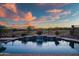 Backyard pool featuring tiered waterfall and stunning sunset views, perfect for relaxing evenings at 41006 N Noble Hawk Way, Anthem, AZ 85086