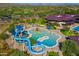 Aerial view of a vibrant water park with colorful slides, splash pad, and surrounding lounge chairs and landscaping at 41006 N Noble Hawk Way, Anthem, AZ 85086