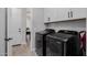 Modern laundry room with black front load washer and dryer set, upper cabinets and tile floor at 4834 S Meteor --, Mesa, AZ 85212