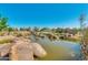 Scenic view of community pond featuring rock landscaping, mature trees, and a blue sky backdrop at 4834 S Meteor --, Mesa, AZ 85212