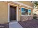 Charming home exterior with stone accents and a well-manicured lawn, welcoming visitors with a dark wood front door at 504 N Ranger Trl, Gilbert, AZ 85234