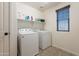 Functional laundry room with washer, dryer, shelving, and window, providing ample space for laundry tasks at 504 N Ranger Trl, Gilbert, AZ 85234