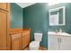 Cozy half bathroom with a storage cabinet, oak trim, a white toilet, and a vanity sink at 648 W Cobblestone Dr, Casa Grande, AZ 85122