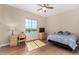 Sunlit bedroom featuring wood floors, a ceiling fan, and a large window at 7630 E Knoll St, Mesa, AZ 85207