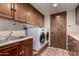 Laundry room with front-load washer, dryer, utility sink, and wood cabinets at 7719 W Bluefield Ave, Glendale, AZ 85308