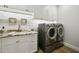 Functional laundry room with modern washer and dryer, sink, and storage cabinets at 8832 E Wethersfield Rd, Scottsdale, AZ 85260