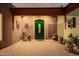 Charming green front door framed by potted plants and set against a brick paved courtyard at 8924 E Charter Oak Dr, Scottsdale, AZ 85260