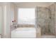 Bright bathroom showcasing soaking tub, shower with neutral toned tile, and a large window at 9012 E Sutton Dr, Scottsdale, AZ 85260