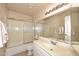 Bathroom featuring a tub/shower combo with glass doors and a white vanity at 9012 E Sutton Dr, Scottsdale, AZ 85260