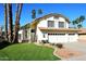 Charming two-story home with a three-car garage, tile roof, desert landscaping, and palm trees at 9012 E Sutton Dr, Scottsdale, AZ 85260