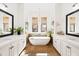 Bright bathroom with a freestanding tub, dual vanities, wood-look tile floors, and a decorative chandelier at 9280 E Thompson Peak Pkwy # 29, Scottsdale, AZ 85255