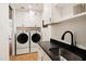 Bright laundry room features a black countertop, sink, and cabinets with modern washer and dryer at 9280 E Thompson Peak Pkwy # 29, Scottsdale, AZ 85255