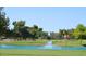 Scenic view of the lush golf course with a water feature, trees, and a red flag marking the green at 9576 E Fairway Blvd, Sun Lakes, AZ 85248