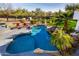 Resort-style pool surrounded by lush landscaping, rock features, and lounge chairs at 10800 E Cactus Rd # 7, Scottsdale, AZ 85259