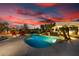 Stunning pool area with a tropical setting, a waterfall, and an evening sky at 10800 E Cactus Rd # 7, Scottsdale, AZ 85259
