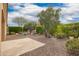 Well-maintained backyard with gravel landscaping, mature trees, and a stone patio at 12957 W Hummingbird Ter, Peoria, AZ 85383