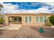 Charming backyard features a covered patio, gravel landscaping, and a view of the home's tan stucco exterior at 12957 W Hummingbird Ter, Peoria, AZ 85383