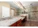 This bathroom features a dual sink vanity with granite countertops and a glass enclosed shower at 12957 W Hummingbird Ter, Peoria, AZ 85383