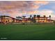 Stunning clubhouse with expansive windows, palm trees, and a well-manicured lawn at sunset at 12957 W Hummingbird Ter, Peoria, AZ 85383