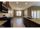 A well-lit kitchen with stainless steel appliances, tile floors, dark wood cabinets, and granite countertops at 13812 W Remuda Dr, Peoria, AZ 85383