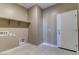 Functional laundry room with storage shelf, tiled floors, and exterior door at 13812 W Remuda Dr, Peoria, AZ 85383