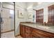 Bathroom featuring granite countertop with wooden cabinets, large mirror with vanity lighting, and a glass door shower at 14360 E Desert Cove Ave, Scottsdale, AZ 85259