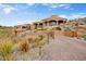 Grand Southwestern-style home features desert landscaping, a circular design, and a paved driveway leading to the gated entrance at 14360 E Desert Cove Ave, Scottsdale, AZ 85259